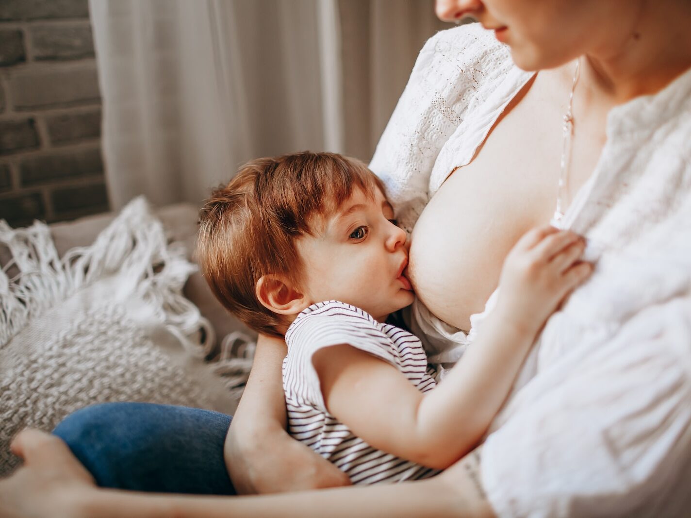 woman in white tank top carrying baby in black and white stripe onesie