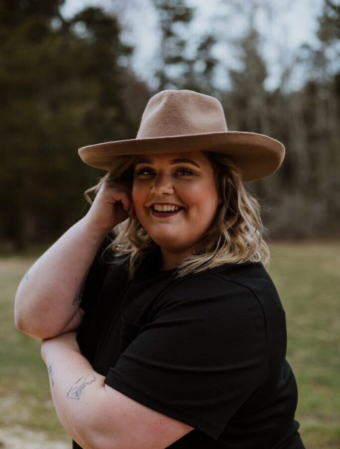 woman in black sleeveless dress wearing brown fedora hat