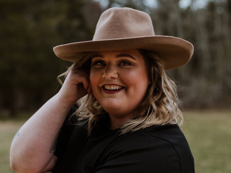 woman in black sleeveless dress wearing brown fedora hat