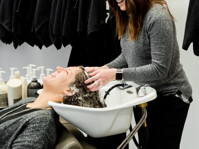 woman in gray sweater holding white clothes hanger