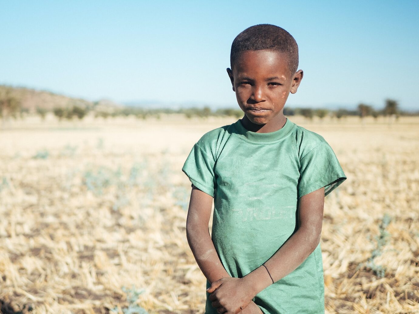 boy standing and holding his arm
