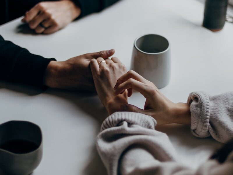 person in black long sleeve shirt holding white ceramic mug
