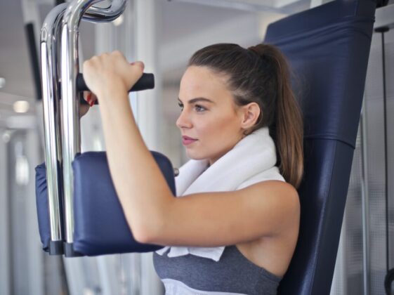 Young determined sportswoman doing exercise on weight machine in modern sports club