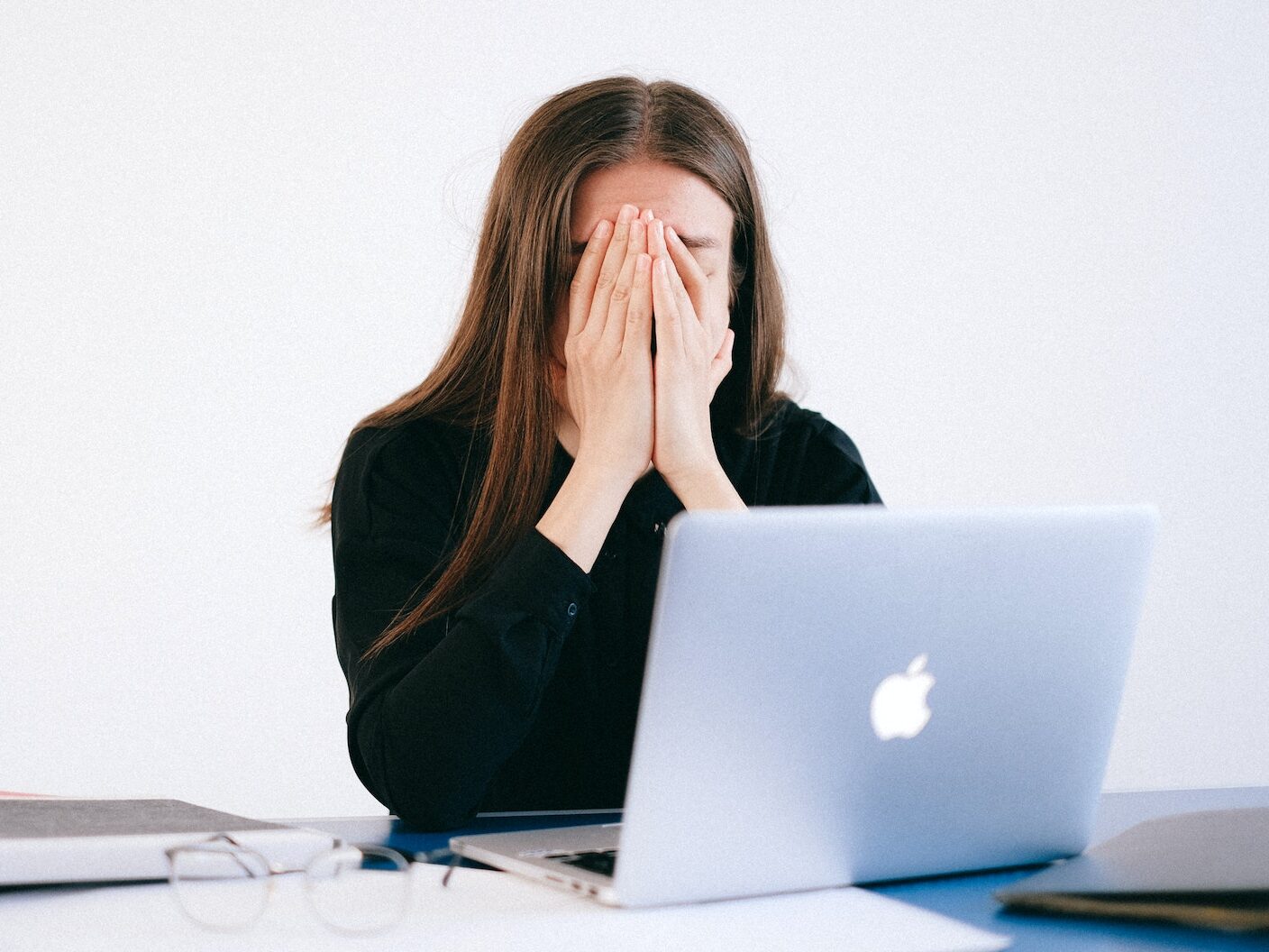 Woman With Hands on her Face in front of a Laptop