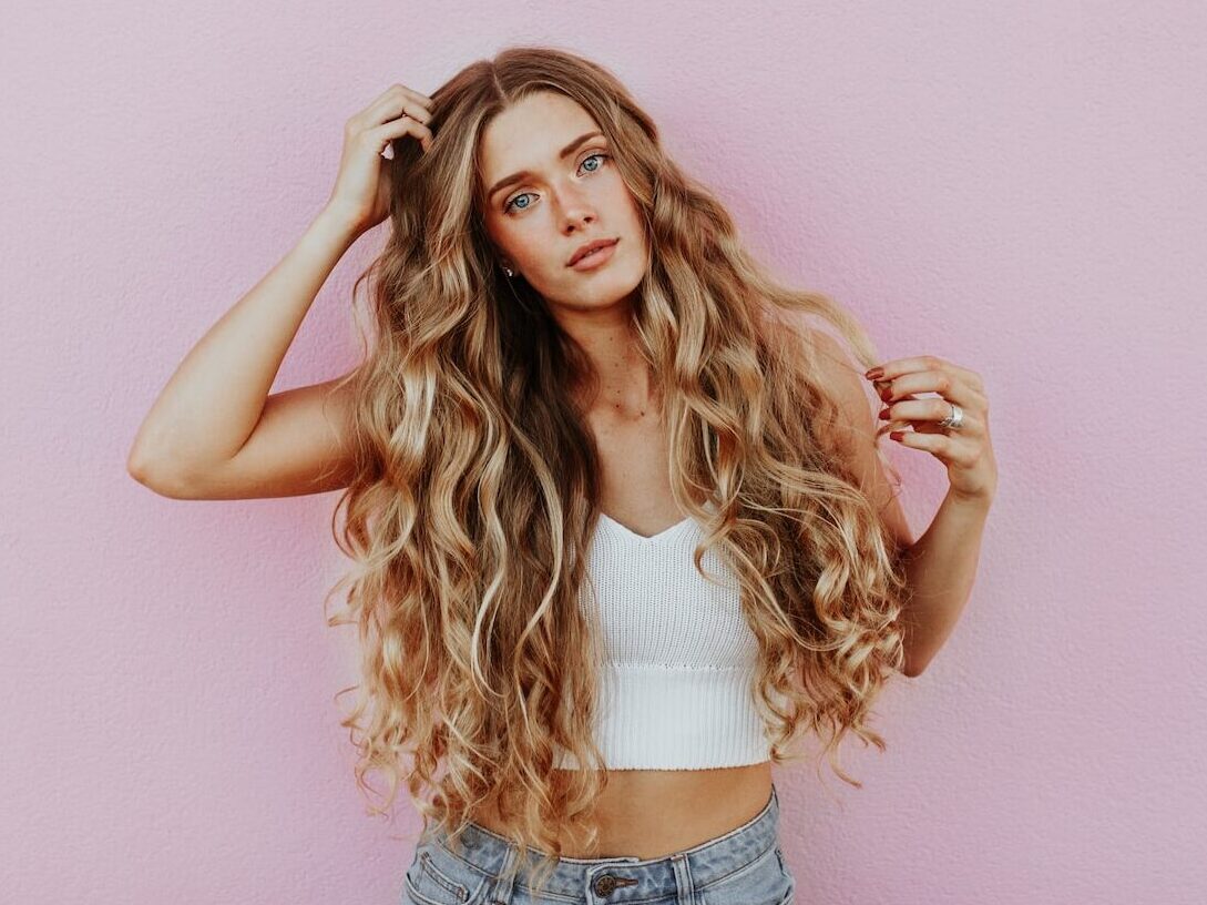woman standing next to pink wall while scratching her head