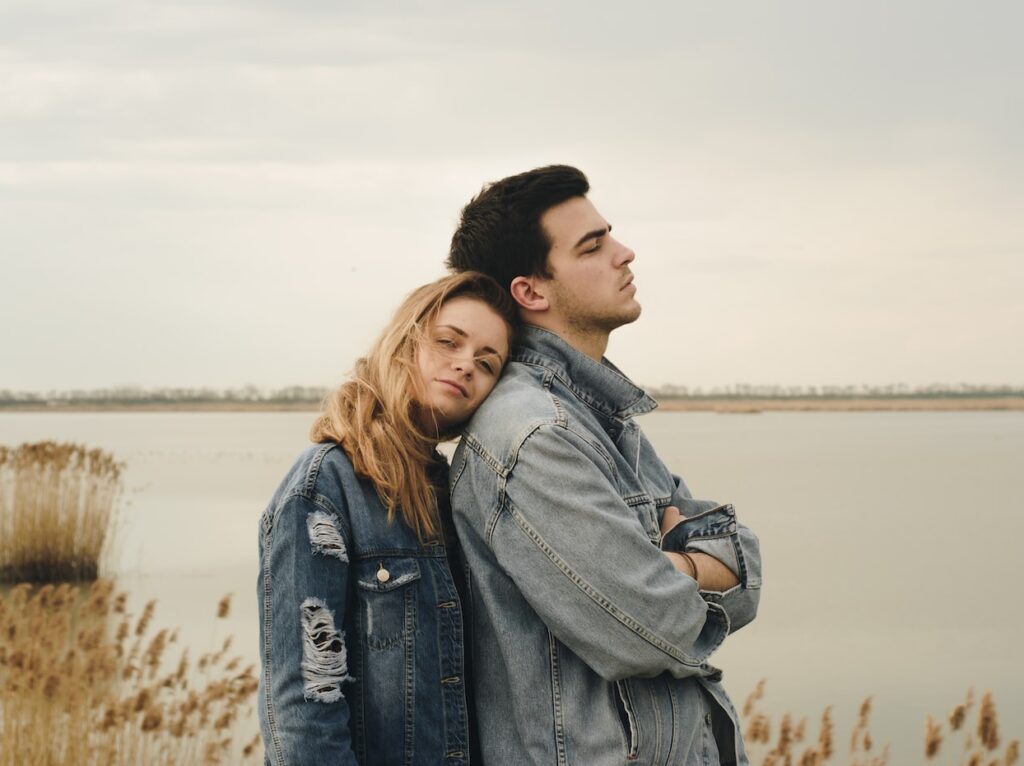 - ČasProŽeny.cz woman in blue denim jacket leaning on man's shoulder near body of water