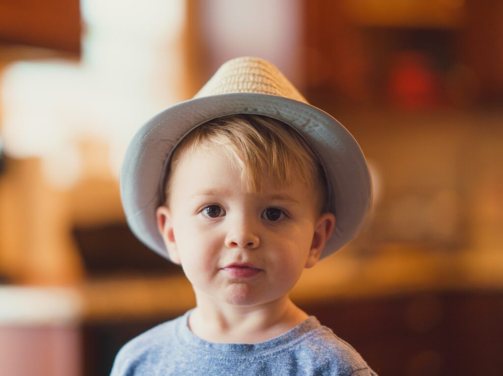 closeup photo of boy wearing brown fedora hat