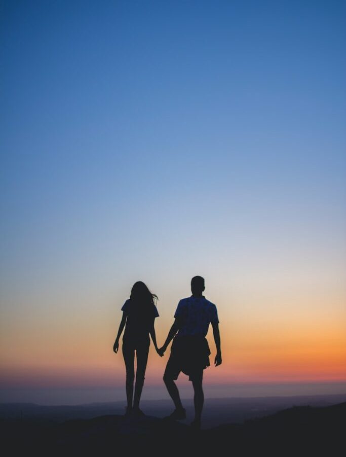 man and woman holding hands in silhouette photography