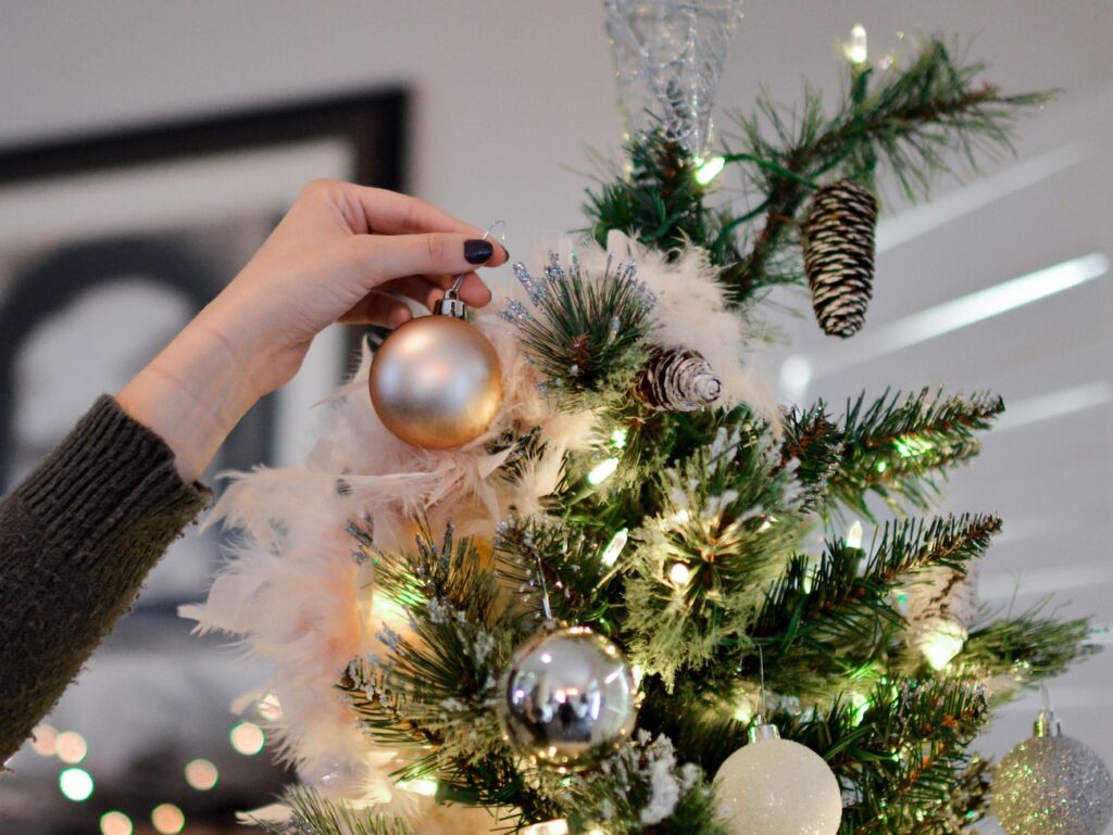 person putting bauble on top of Christmas tree