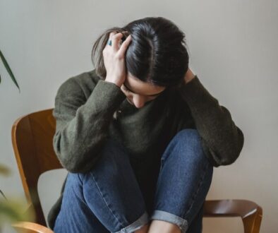 Anxious young woman cover wing ears with hands sitting on chair