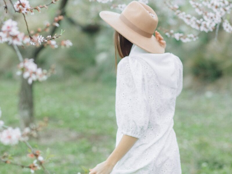 Back View of a Woman Wearing a White Dress and Brown Hat