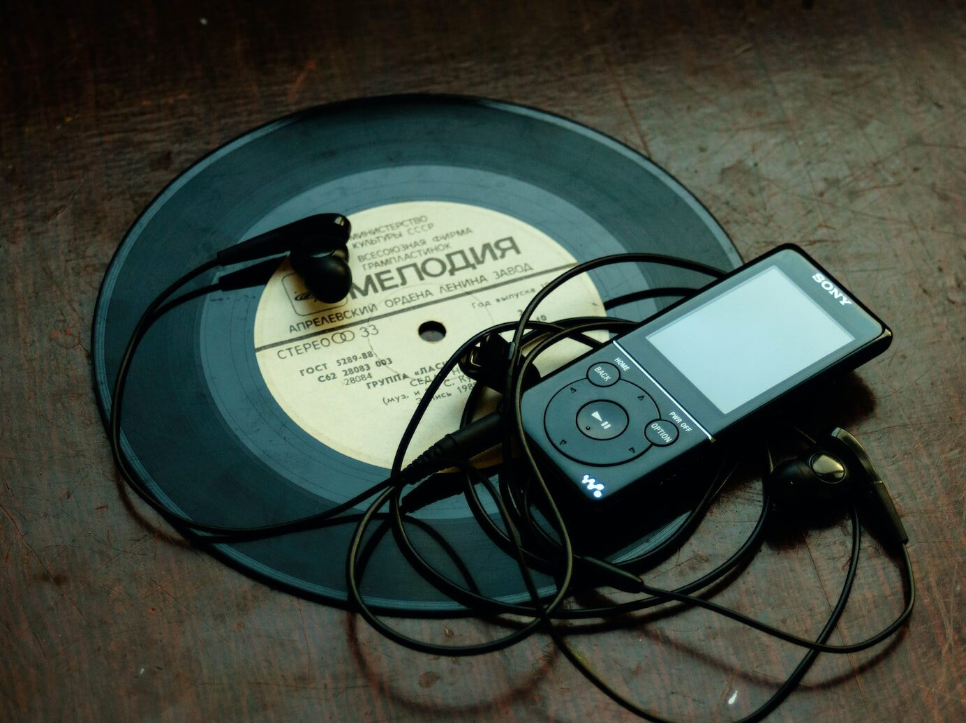 in-ear headphones plugged in black Sony Walkman on vinyl record
