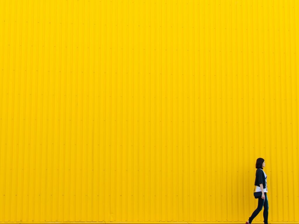 woman wearing black top standing near yellow wall