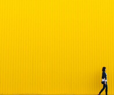 woman wearing black top standing near yellow wall