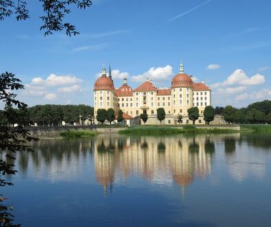 white and brown concrete building near body of water under blue sky during daytime