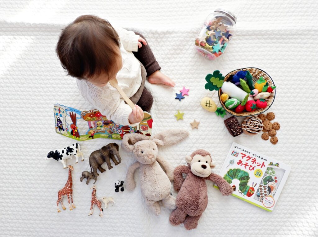 boy sitting on white cloth surrounded by toys