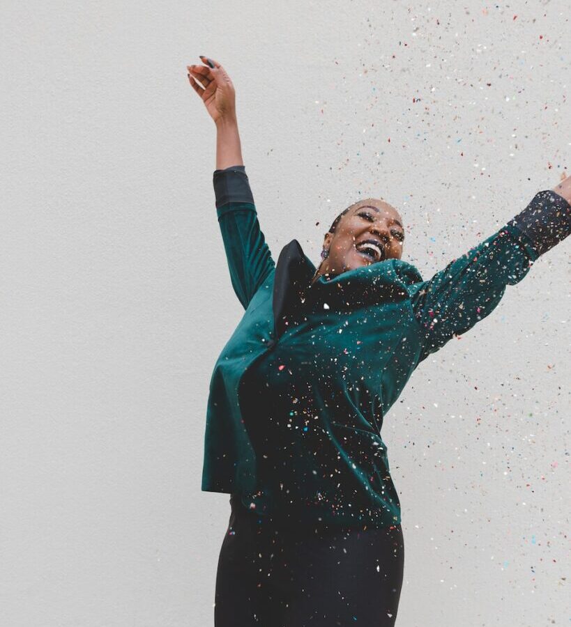 woman in green jacket raising her hands