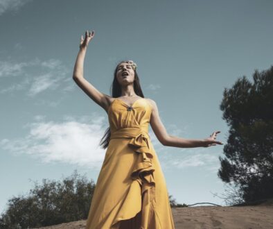 Woman in Yellow Sleeveless Dress Standing on Brown Sand