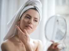 Selective Focus Portrait Photo of Woman With a Towel on Head Looking in the Mirror