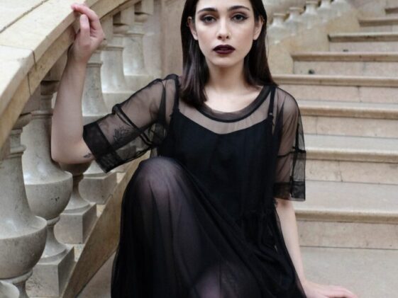 Gothic woman in black outfit sitting on stairs