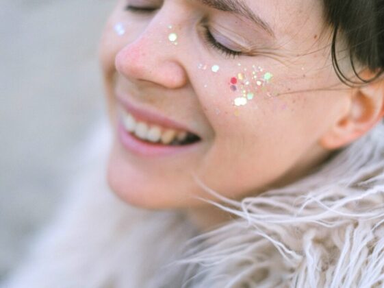 Side view of female with glitter laughing and enjoying moment with closed eyes