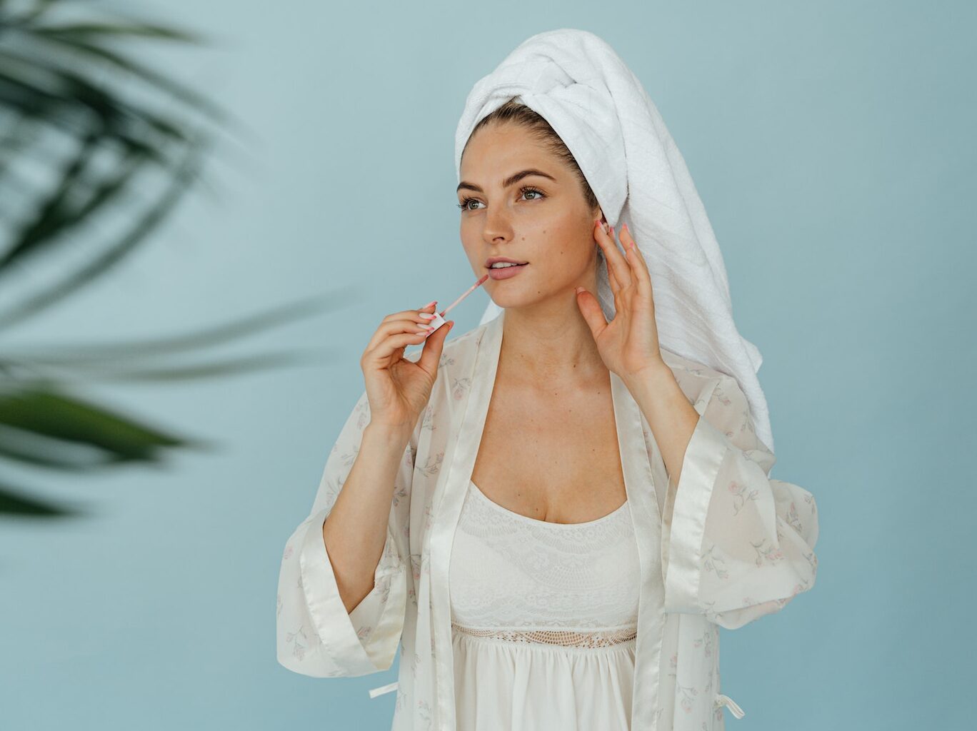 A Beautiful Woman in White Robe Applying Lip Gloss