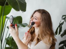 Photo of a Blonde Woman Applying Makeup on Her Cheeks