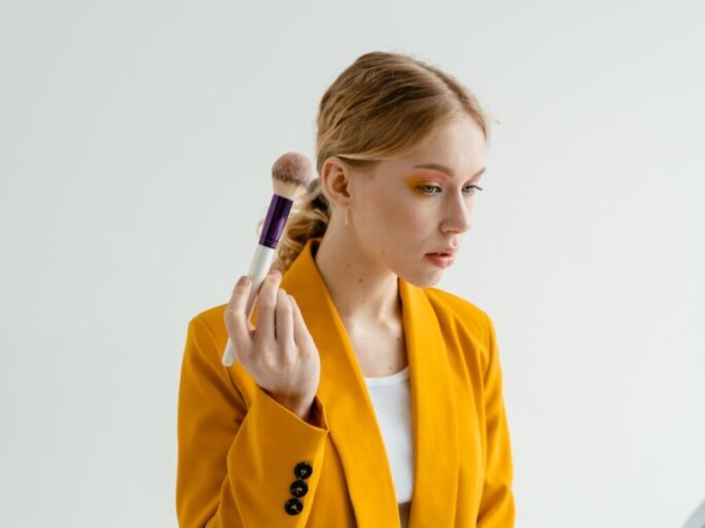 Woman in Yellow Coat Holding Makeup Brush