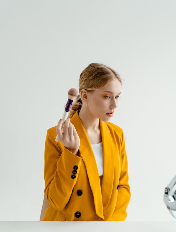 Woman in Yellow Coat Holding Makeup Brush
