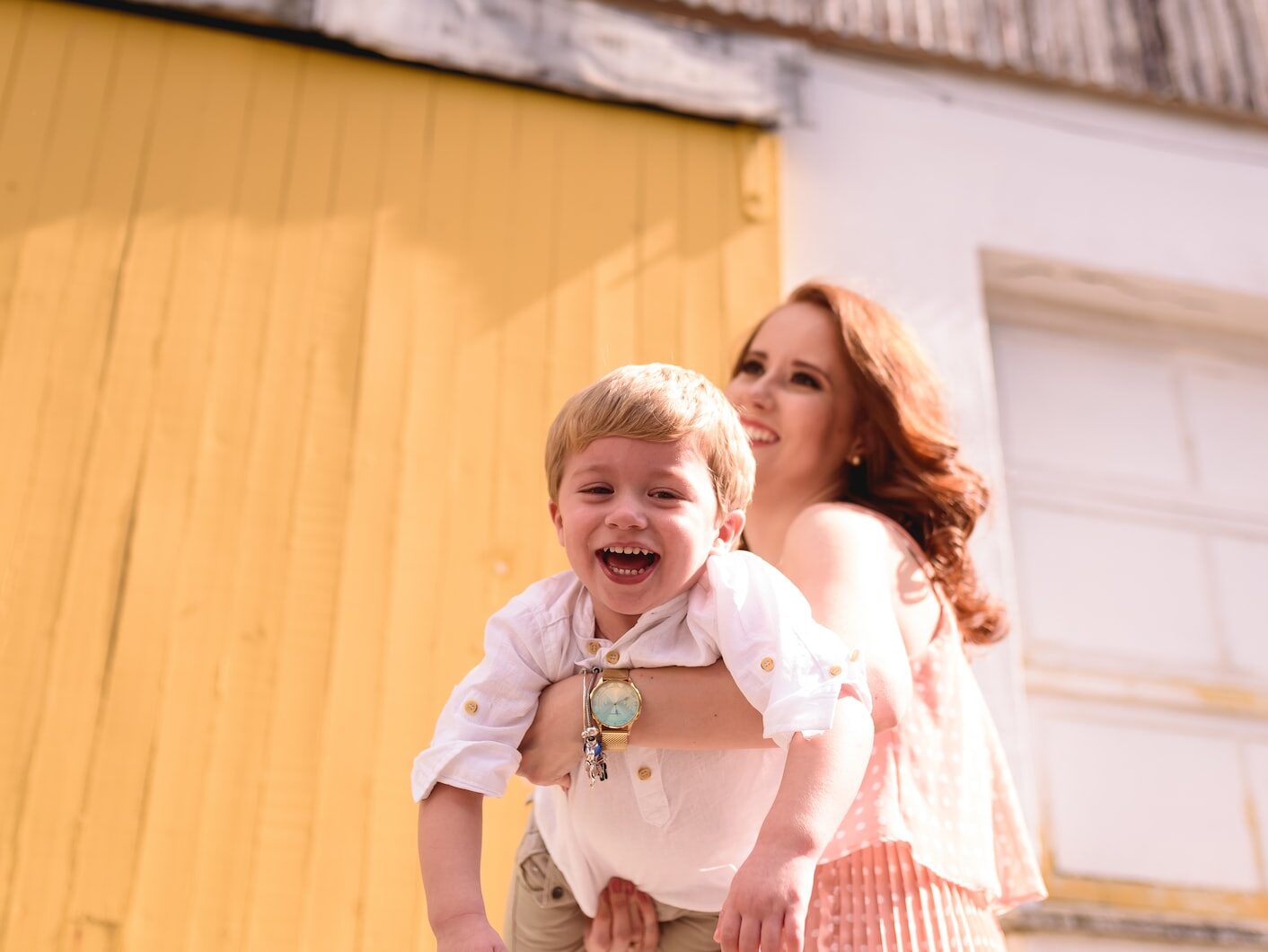 woman in blue and white plaid dress shirt carrying girl in white shirt
