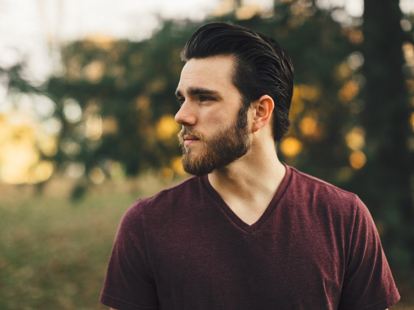 man wearing maroon V-neck t-shirt in forest