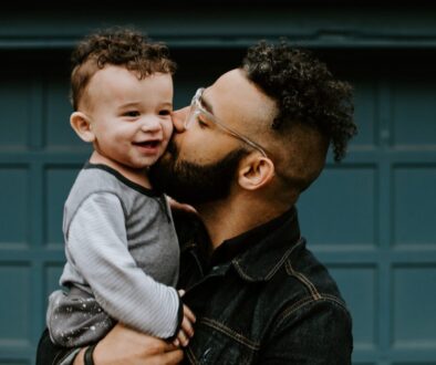 man carrying baby boy and kissing on cheek