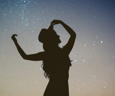 silhouette of woman holding hat in blue and gray nebula