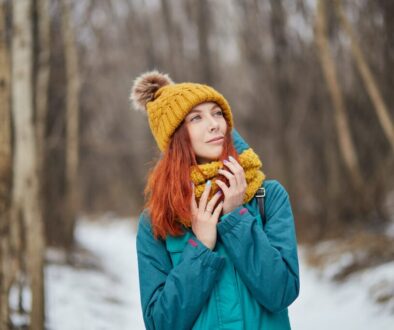 woman in blue jacket and brown knit cap standing on snow covered ground during daytime
