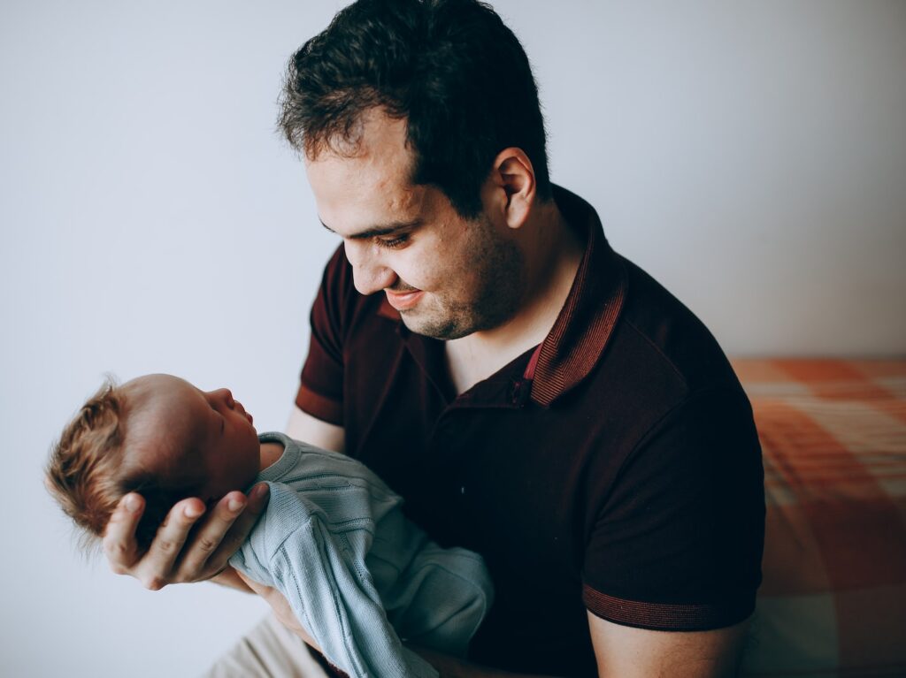 man in black polo shirt carrying baby