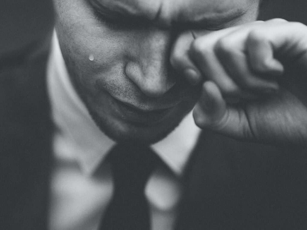 man wiping his tears