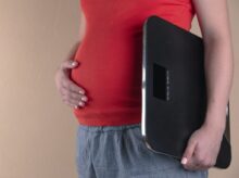 pregnant woman touching her belly and carrying a digital bathrooms cale
