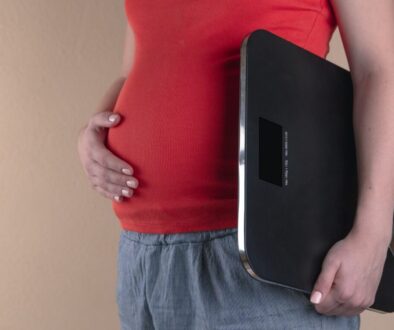 pregnant woman touching her belly and carrying a digital bathrooms cale