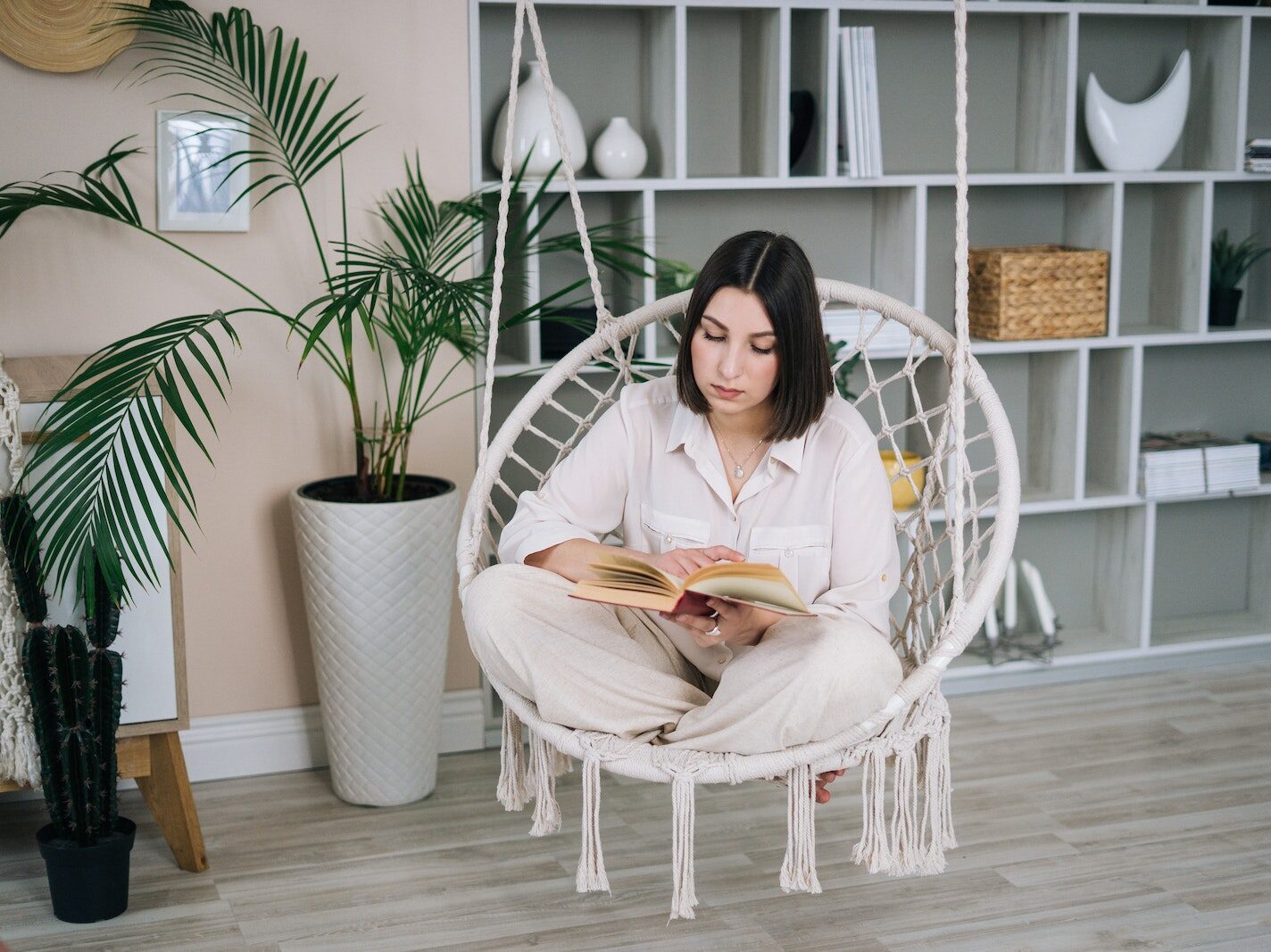 Woman in White Long Sleeve Shirt Sitting on White Wicker Chair
