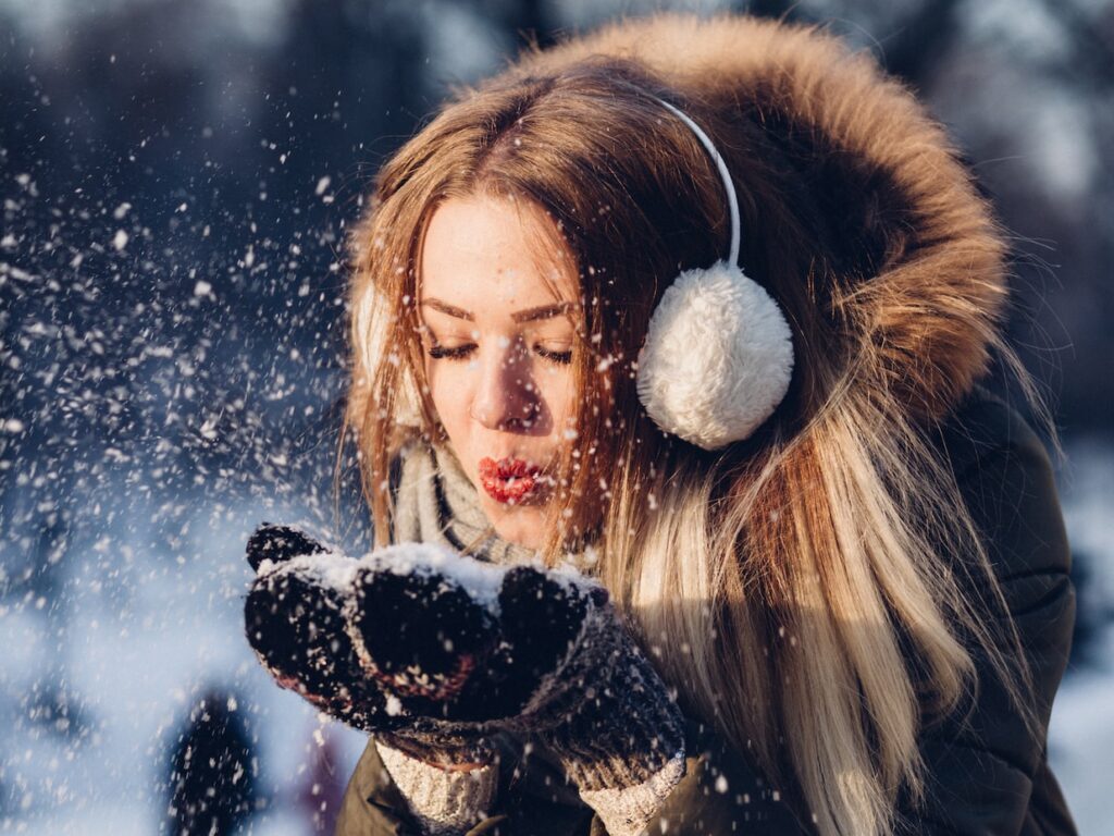 woman blowing snow on her hands