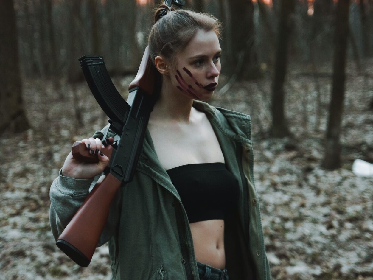 woman in black leather jacket holding black rifle