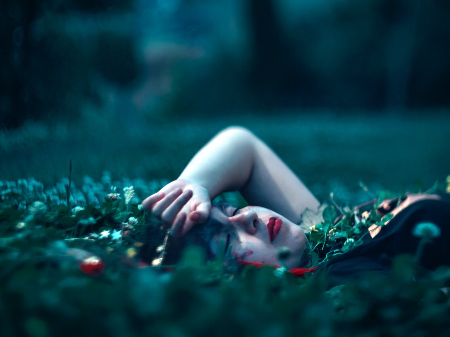 woman closing eyes lying on green grass