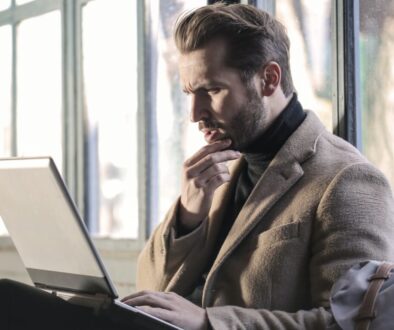 man holding his chin facing laptop computer