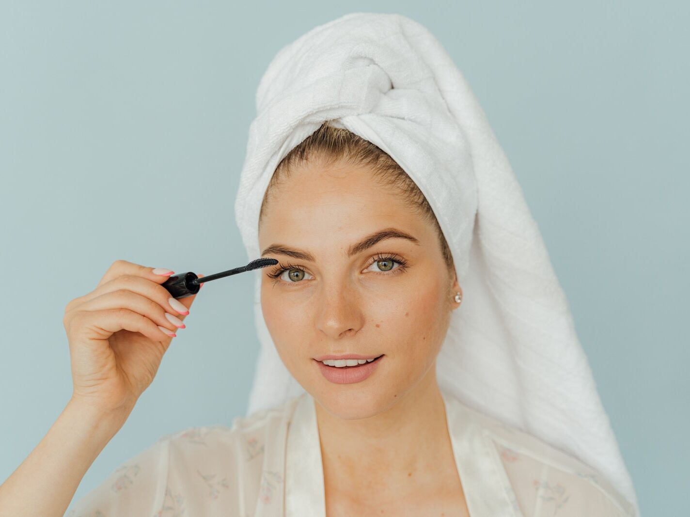 Woman in White Top and Head Towel Applying Mascara on Eyelashes