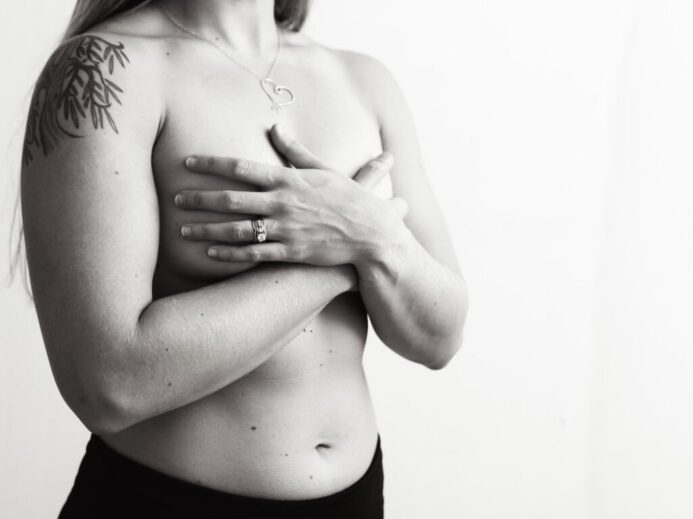 a black and white photo of a woman with tattoos on her chest
