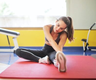 Woman in Black Sports Bra and Black Legging Sitting on Red Yoga Mat