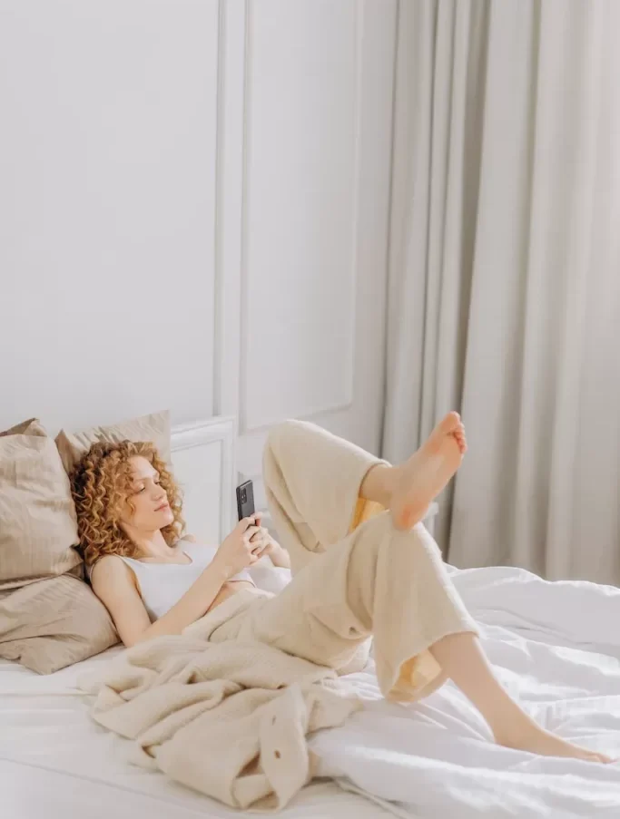 Woman Lying on Bed While Using a Cellphone