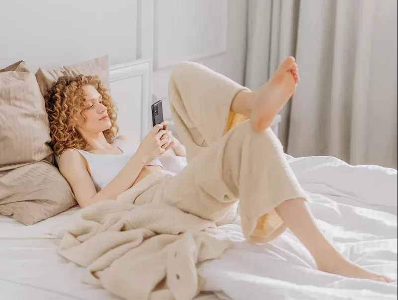 Woman Lying on Bed While Using a Cellphone