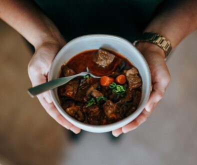 person holding white ceramic bowl with soup