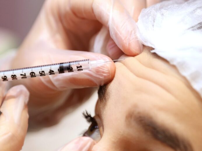 a woman getting her eyebrows examined by a doctor